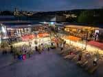 Vista nocturna del patio exterior de Steelyard en Sheffield con mesas y luces