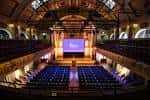 Sala principal configurada para evento con escenario y pantalla de proyección