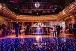 Evento social en curso con pista de baile iluminada y barra central