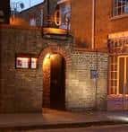 Fachada nocturna del 606 Club con entrada iluminada y detalles arquitectónicos en ladrillo