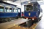 Dos vagones del Tramvia Blau dentro de la cochera, uno con luces encendidas