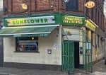 Fachada frontal del pub con letrero verde y toldo