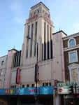 Vista exterior de la fachada del Gaumont State Cinema con su torre distintiva y letrero