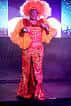 Drag queen con vestuario brillante y peluca naranja en el escenario