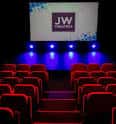 Vista del escenario con luces de color y pantalla que muestra el logo 'JW Theatre'