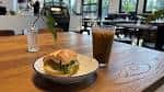 Interior del café con mesa de madera, plato de comida y bebida fría