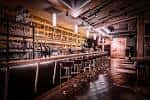 Interior del bar con barra larga y estanterías de botellas iluminadas