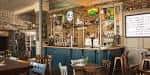 Interior del local Bunkers Hill con barra de bar, mesas y decoración rústica