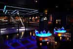 Vista del interior del club con mesas iluminadas y barra