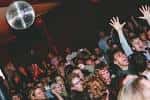 Público disfrutando de un evento con bola disco en el techo del The Lexington