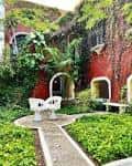 Jardín interior de la hacienda con bancos blancos y vegetación exuberante