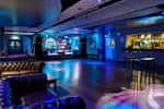 Espacio interior moderno con iluminación azul, sofás y barra de bebidas