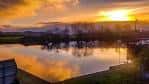 Paisaje natural al atardecer con reflejos en el agua y vegetación circundante