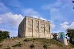 Castillo de Norwich visto desde una colina bajo cielo azul con nubes