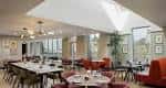 Sala de eventos interior con mesas redondas y grandes ventanales