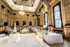 Salón interior decorado para evento con mesas blancas y candelabros