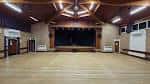Interior del salón de eventos con escenario y suelo de madera