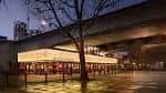 Plaza frontal del BFI Southbank por la noche con reflejos en el suelo mojado y silueta de árbol