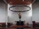 Interior del altar de la iglesia con decoración circular colgante y bancos de madera
