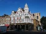 Vista exterior del New Cross Inn con su fachada victoriana blanca y detalles ornamentales
