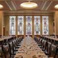 Sala de reuniones con mesas largas y ventanas de vitrales