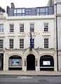 Vista frontal del edificio de Sotheby's en Londres con bandera británica colgando