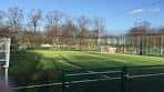 Campo de fútbol en Down Lane Park con vallas y árboles al fondo