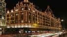 Fachada iluminada de Harrods por la noche con luces decorativas