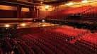 Interior del auditorio con butacas rojas y escenario