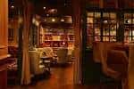 Sala de estar interior con sofás tapizados, mesas bajas y estanterías de libros al fondo