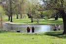 Vista del lago en Cutteslowe Park con personas paseando