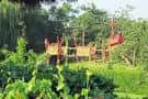 Estructura de madera y tobogán rojo en zona verde del parque