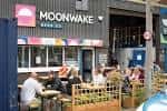Vista exterior del pub Moonwake Beer Co. con clientes sentados en la terraza