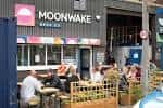 Vista exterior del pub Moonwake Beer Co. con clientes sentados en la terraza