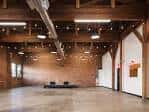 Interior del espacio de eventos con vigas de madera y suelo de concreto