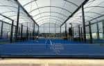 Pista de pádel o tenis cubierta con suelo azul y estructura metálica