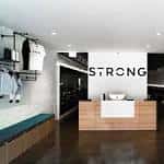 Recepción del centro STRONG Pilates con mostrador de madera y logo en la pared