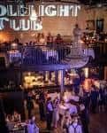 Interior del The Candlelight Club con barra superior, iluminación cálida y clientes disfrutando
