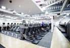 Interior de sala de fitness con equipamiento deportivo alineado y techo iluminado
