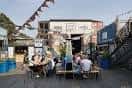 Zona exterior de Peckham Levels con personas sentadas en mesas al aire libre