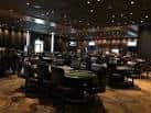 Sala de póker interior del casino con mesas de juego y ambiente oscuro