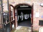 Entrada arqueada al museo con puertas abiertas mostrando el interior oscuro