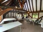 Interior del ático con vigas de madera expuestas y mesas preparadas para eventos