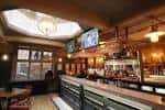 Interior del bar con barra de madera y pantallas de televisión