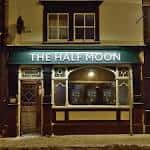 Fachada iluminada del pub The Half Moon por la noche