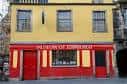 Fachada frontal del Museo de Edimburgo con letrero rojo y ventanas clásicas