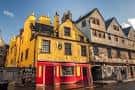 Exterior del Museo de Edimburgo al atardecer con cielo azul y reflejos en la calle mojada