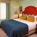 Habitación con cama doble decorada con cojines amarillos y cabecero rojo