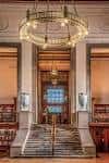 Interior del atrio principal con escalera y lámpara de araña