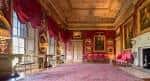 Gran salón interior con tapices rojos, alfombras y mobiliario histórico